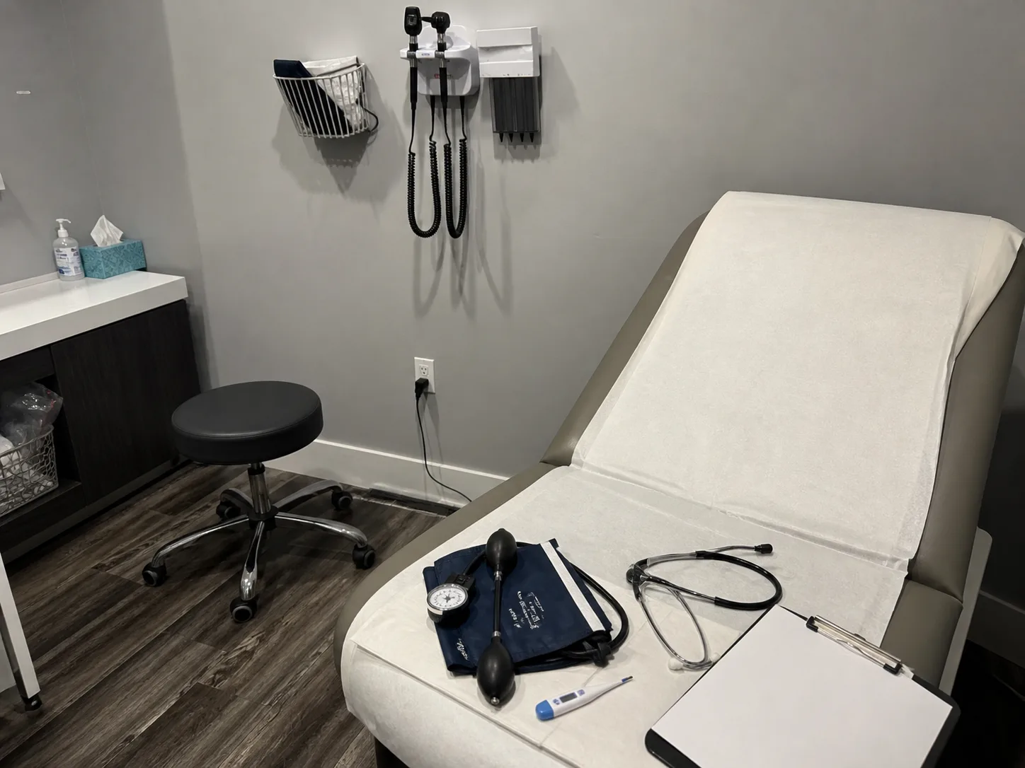 AI-generated visual concept of an exam room prepared for a primary-care checkup; it does not document a specific clinic room, clinician, or procedure.