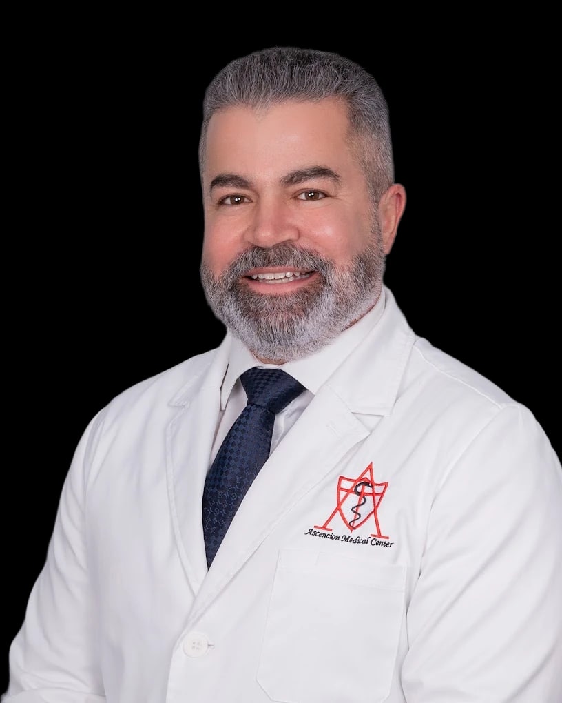 Guido Lopez sonríe con bata blanca en un retrato frontal.